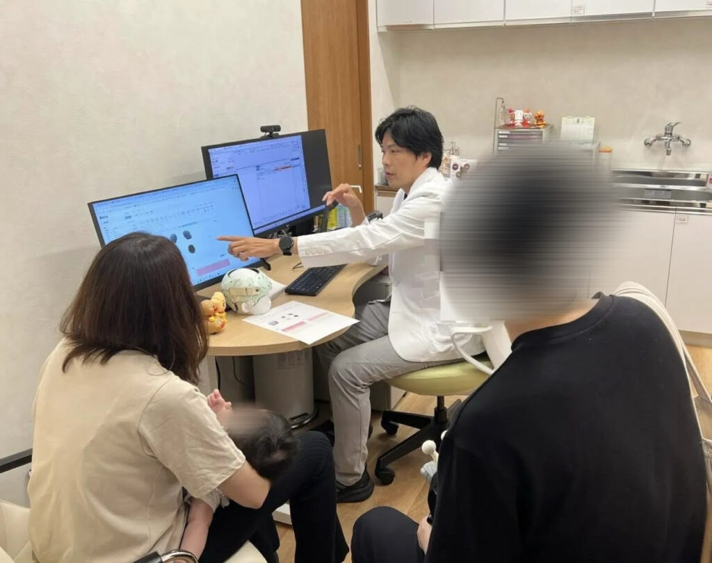 赤ちゃんの頭の測定結果について医師が保護者へ説明している様子